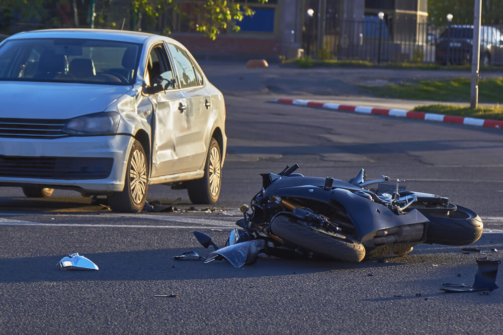 Motorcycle on ground next to vehicle after an accident