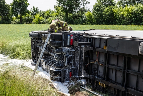 Overturned semi truck in a field with emergency responders on scene, representing investigations managed by a Lincoln truck accident lawyer.