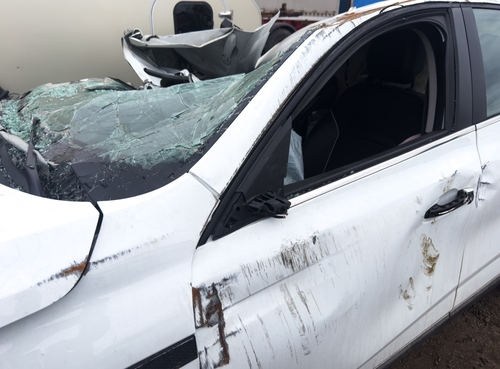 A severely damaged white vehicle with shattered glass and deep side impact marks, illustrating cases reviewed by a Lincoln car accident lawyer.