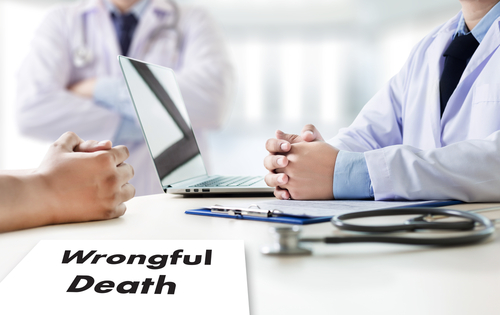 Two people meeting with a doctor at a desk with a document labeled “Wrongful Death,” representing discussions often handled by a Lincoln wrongful death lawyer.